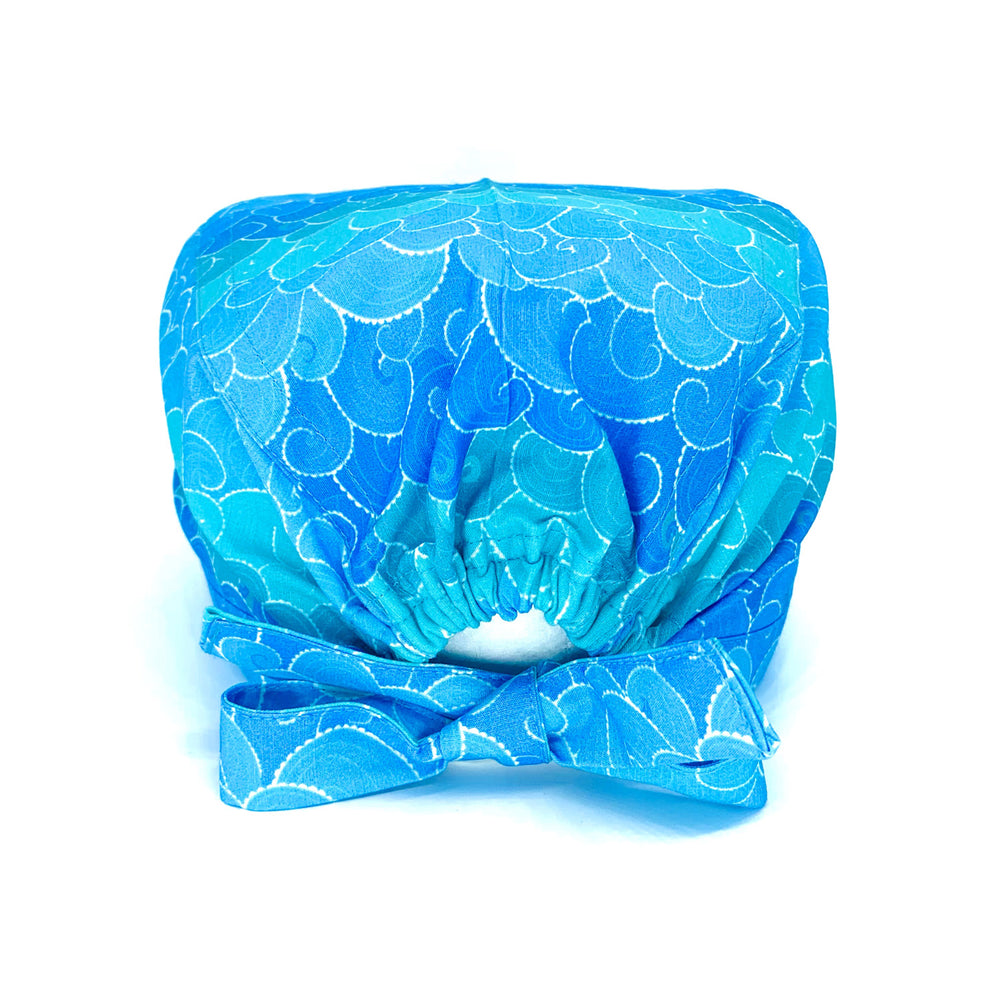 Foto vista retro di cuffia chirurgica con disegnate le onde del mare stilizzate in varie sfumature di azzurro. laccio ed elastico per contenere anche capelli lunghi